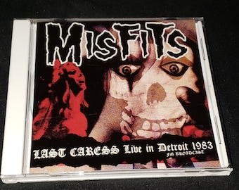 Może przedstawiać: Pudełko na płytę CD z czarno-białym obrazkiem czaszki na czarno-białym tle. Na przedniej stronie pudełka widnieje tekst "Misfits Last Caress Live in Detroit 1983 FM Broadcast".