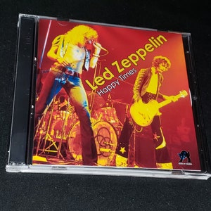 May include: A CD case with a red background featuring a photo of the band Led Zeppelin. The band members are playing instruments and the text "Led Zeppelin Happy Times" is printed on the case.