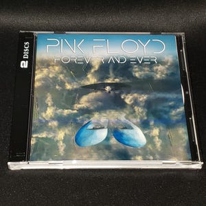 May include: A Pink Floyd "Forever and Ever" CD album in a clear plastic case. The album cover features a surreal image of a cloudy sky with a flying object and two blue, eye-shaped objects. The case is labeled "2 Discs".