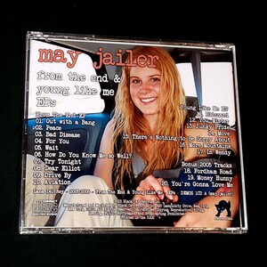 May include: A CD case with a black and white image of a black cat on the back. The front of the case features a photo of a young woman with blonde hair driving a car. The text on the front of the case reads "may jailer from the end & young like me EPS". The back of the case lists the songs on the CD, including "Out with a Bang", "Peace", "Bad Disease", "For You", "Wait", "How Do You Know Me So Well?", "Try Tonight", "Dear Elliot", "Drive By", "Aviation", "Blizzard", "You, Mister", "Junky Pride", "Move", "There's Nothing to Be Sorry About", "More Mountains", "In Wendy", "Fordham Road", "Money Hunny", and "You're Gonna Love Me".