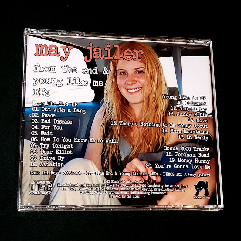 May include: A CD case with a black and white image of a black cat on the back. The front of the case features a photo of a young woman with blonde hair driving a car. The text on the front of the case reads "may jailer from the end & young like me EPS". The back of the case lists the songs on the CD, including "Out with a Bang", "Peace", "Bad Disease", "For You", "Wait", "How Do You Know Me So Well?", "Try Tonight", "Dear Elliot", "Drive By", "Aviation", "Blizzard", "You, Mister", "Junky Pride", "Move", "There's Nothing to Be Sorry About", "More Mountains", "In Wendy", "Fordham Road", "Money Hunny", and "You're Gonna Love Me".