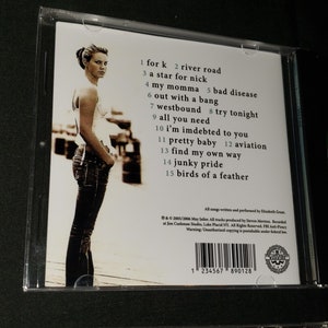 May include: CD case with a white background and a photo of a woman in jeans and a white shirt. The text on the back of the case lists the songs on the album: "for k", "river road", "a star for nick", "my momma", "bad disease", "out with a bang", "westbound", "try tonight", "all you need", "i'm indebted to you", "pretty baby", "aviation", "find my own way", "junky pride", and "birds of a feather".