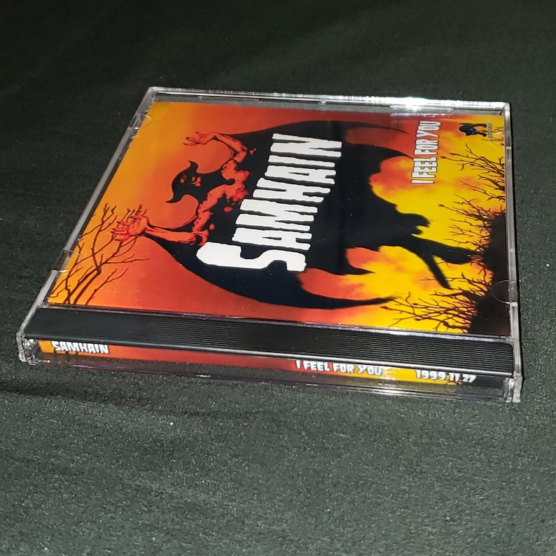 K&ouml;nnte beinhalten: Ein CD-Geh&auml;use mit einem schwarzen und roten Design. Die Vorderseite des Geh&auml;uses zeigt eine schwarze Silhouette eines D&auml;mons mit dem Bandnamen "SAMHAIN" in wei&szlig;en Buchstaben. Der Titel des Albums, "I FEEL FOR YOU", ist in wei&szlig;en Buchstaben auf der rechten Seite des Geh&auml;uses geschrieben. Das Jahr "1999.11.27" ist in der unteren rechten Ecke des Geh&auml;uses gedruckt.