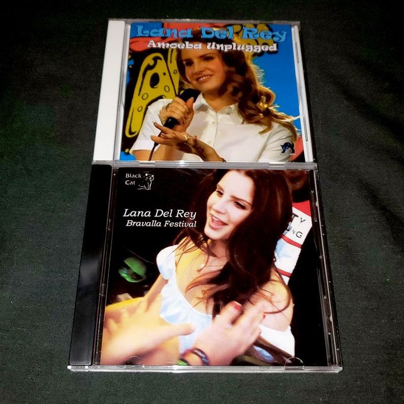 K&ouml;nnte beinhalten: Zwei CDs mit Lana Del Rey. Die obere CD tr&auml;gt den Titel "Amoeba Unplugged" und die untere CD den Titel "Bravalla Festival". Beide CDs zeigen ein Foto von Lana Del Rey auf der Vorderseite.