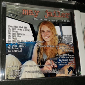 May include: A CD case with a photo of a young woman on the front. The back of the case lists the songs on the CD, including "Out with a Bang", "Peace", "Bad Disease", "For You", "Wait", "How Do You Know Me So Well?", "Try Tonight", "Dear Elliot", "Drive By", "Aviation", "Blizzard", "You, Mister", "Junky Pride", "Move", "There's Nothing to Be Sorry About", "More Mountains", "In Wendy", "Fordham Road", "Money Hunny", and "You're Gonna Love Me". The text "Lana Del Rey - 2005-2006 - From The End & Young Like Me EPs - DEMOS ICD A (may jailer)" is printed at the bottom of the case.