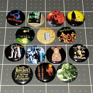 May include: A collection of black round buttons featuring the band Alice in Chains. Each button has a different design, including album art, band logos, and text. The buttons are arranged on a gray grid.