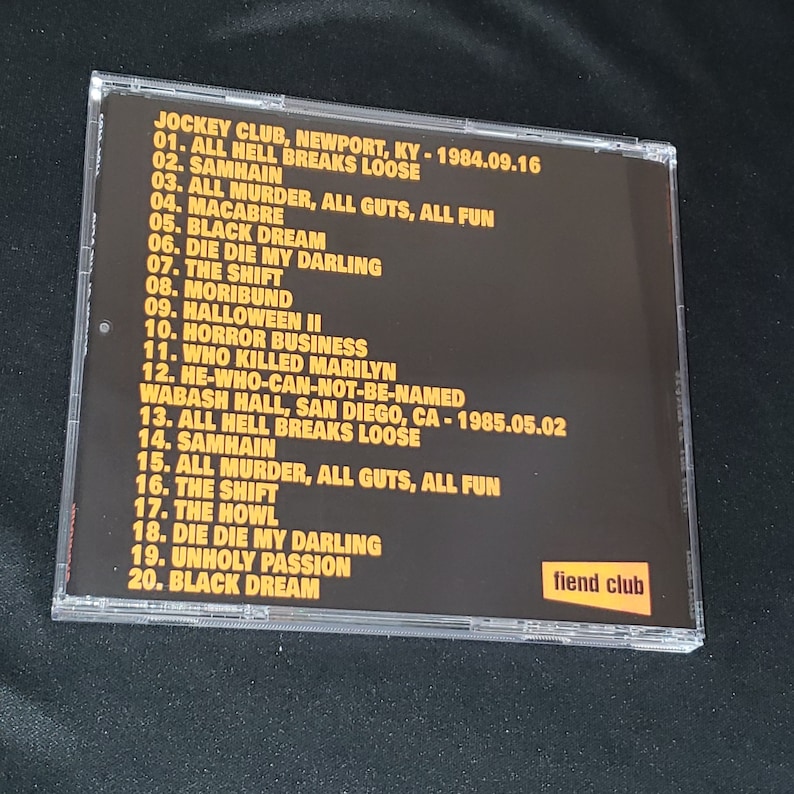 May include: A black CD case with yellow text listing the tracklist for the album "Jockey Club" by the band "Fiend Club". The album was released in 1984 and 1985. The text on the case reads "Jockey Club, Newport, KY - 1984.09.16" and "Wabash Hall, San Diego, CA - 1985.05.02".