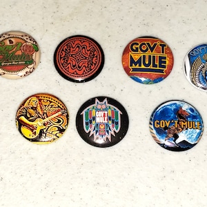 May include: Six round buttons with different designs. The buttons feature the band Gov't Mule. One button has a black background with a colorful design, another has a blue background with a horse, and another has a red background with the band's name.