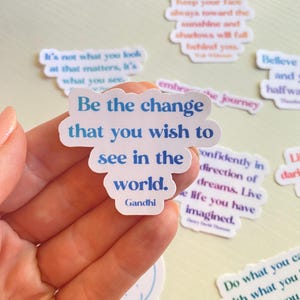 May include: A collection of colorful stickers with inspirational quotes. The stickers feature a variety of colors and fonts, including blue, pink, green, and white. The quotes include "Be the change that you wish to see in the world. Gandhi", "Keep your face always toward the sunshine and shadows will fall behind you", "Believe and you are halfway there", "Confidently in the direction of your dreams. Live the life you have imagined", and "Do what you can with what you have where you are."