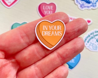 Może przedstawiać: Naklejka w kształcie serca z pomarańczowym tłem i białym tekstem, który brzmi "In Your Dreams".