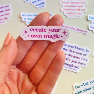 May include: White sticker with pink and purple text that reads "create your own magic" with two small sparkly stars on either side of the text.