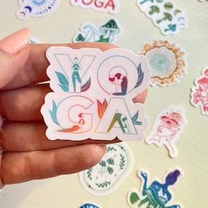 Puede incluir: Una pegatina con la palabra "YOGA" en colores arcoíris. Las letras están delineadas en blanco y cada letra presenta la silueta de una persona haciendo una pose de yoga diferente.