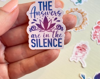 May include: A white sticker with a purple lotus flower and the text "THE Answers are in the SILENCE" in blue and purple lettering.
