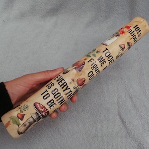 May include: A cylindrical wooden rolling pin featuring a light tan finish with printed illustrations of various mushrooms and the text: lets about TOGETHER WE WILL FIGURE OUT EVERYTHING IS GOIN TO BE OK.