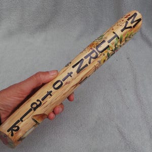 May include: A cylindrical wooden rolling pin featuring a light tan wood grain finish. The surface is decorated with painted botanical illustrations of mushrooms and foliage, and the black text MY TURN TO TALK is printed along the length.