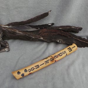 May include: A cylindrical wooden tube with the text "I'M SPEAKING" burnt into the surface, accompanied by small heart shapes. Nearby sits a metallic rabbit figurine, a piece of dark textured bark, and a yellow painted wooden mushroom ornament.