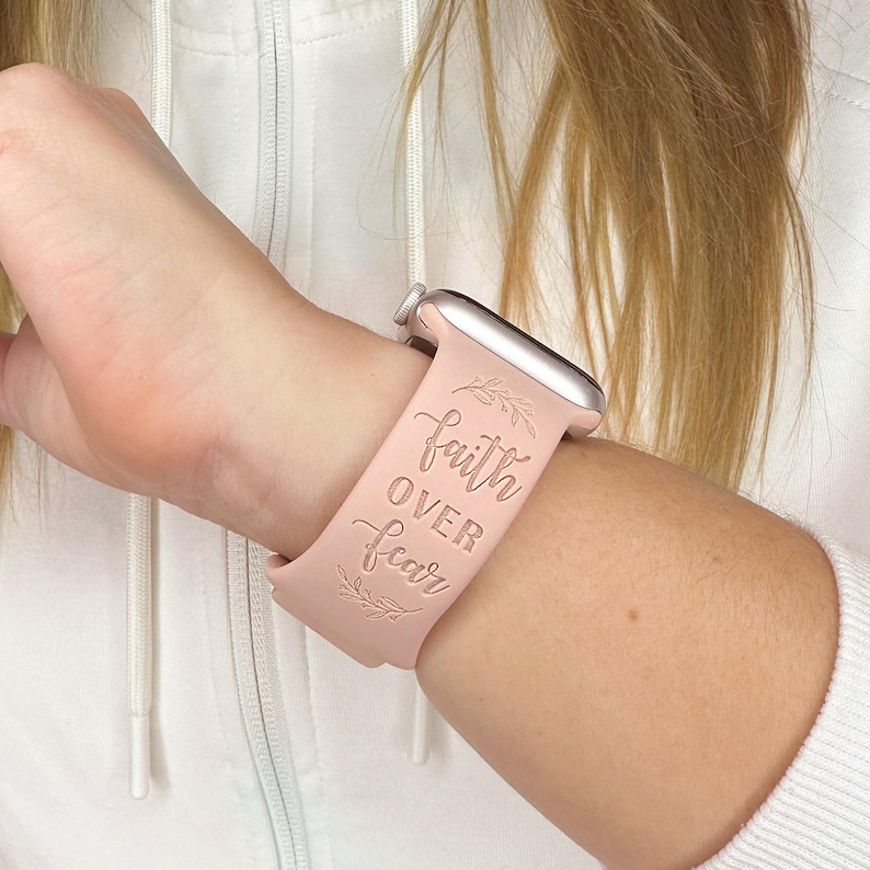 May include: A pink silicone watch band with the words "faith over fear" and a floral design.