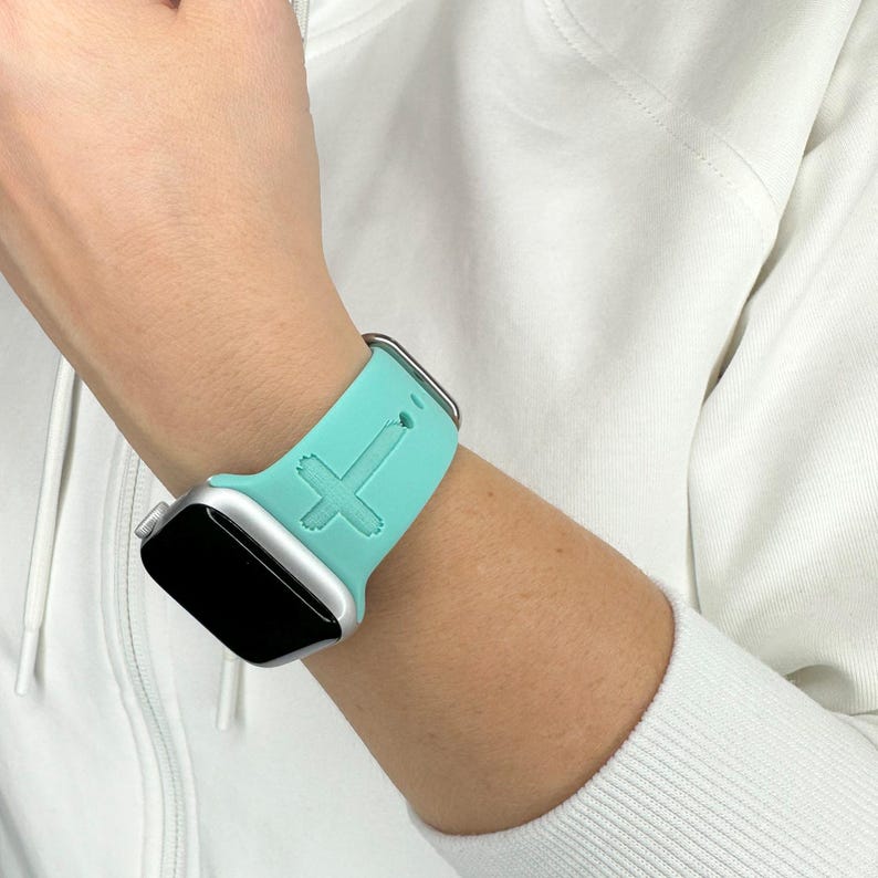 May include: A turquoise silicone Apple Watch band with a raised cross design.