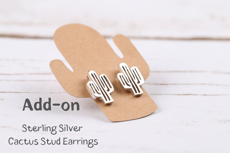 May include: Add-on Sterling Silver Cactus Stud Earrings. Two silver cactus earrings are displayed on a brown card shaped like a cactus.