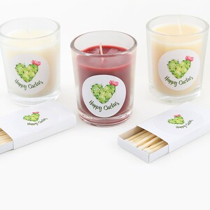 May include: Three glass candle jars with labels that say "Happy Cactus" and a cactus illustration. The candles are white, red, and yellow. A box of matches with a "Happy Cactus" label is also included.