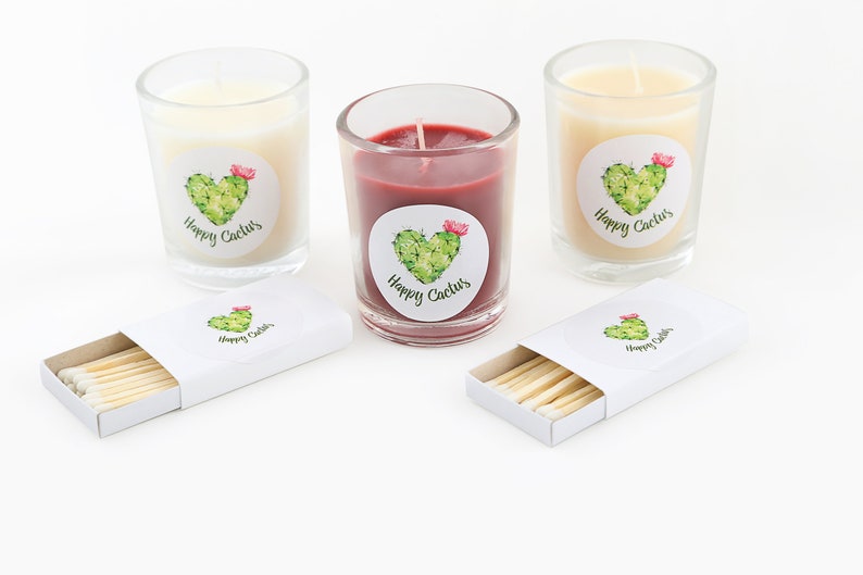 May include: Three glass candle jars with labels that say "Happy Cactus" and a cactus illustration. The candles are white, red, and yellow. A box of matches with a "Happy Cactus" label is also included.