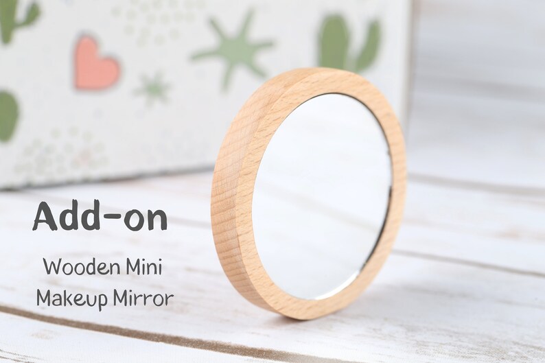 May include: Add-on Wooden Mini Makeup Mirror. A small, round mirror with a wooden frame.
