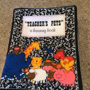 May include: A black and white book with a colorful illustration of animals on the cover. The title of the book is "Teacher's Pets" and the subtitle is "a learning book".