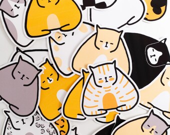 May include: A collection of 14 colourful cat stickers with various poses and patterns. The stickers are all in a cartoon style and feature different colours, including yellow, orange, black, white, and grey.