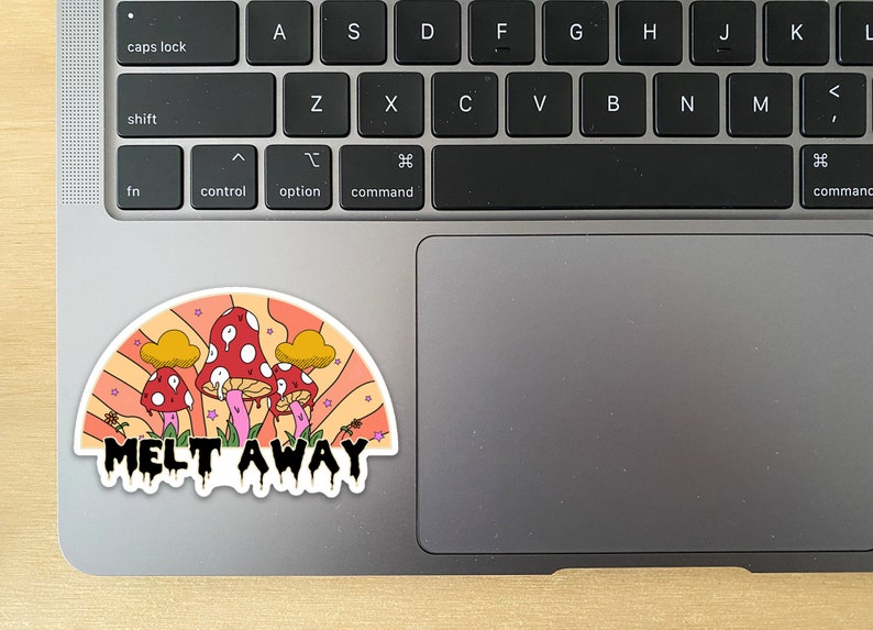 K&ouml;nnte beinhalten: Ein farbenfroher Aufkleber mit einem skurrilen Design von roten Pilzen mit wei&szlig;en Punkten, vor einem Regenbogenhintergrund im Retro-Stil. Der Aufkleber tr&auml;gt den Text "MELT AWAY" in einer tropfenden Schriftart. Der Aufkleber befindet sich auf einem Laptop.