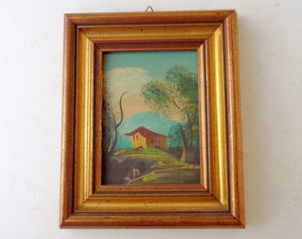 Könnte beinhalten: Gerahmtes Landschaftsgemälde mit einem gelben Haus mit rotem Dach, umgeben von grünen Bäumen und Hügeln. Das Kunstwerk ist in einem goldfarbenen Holzrahmen eingefasst und bietet eine Vintage-Ästhetik.