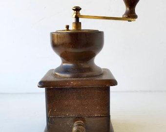 May include: A vintage wooden coffee grinder with a dark brown finish. It features a brass handle and a small drawer. The grinder is rectangular with a square base and a wooden handle on the drawer.