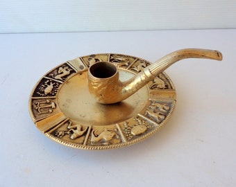 vintage solid brass ashtray with zodiac signs and a pipe for handle, can also be used as a candle holder, diameter 16 cm, weight 470 grams