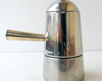 May include: A stainless steel stovetop espresso maker with a gold-toned handle and lid accents. The coffee pot has a classic design, perfect for brewing espresso at home. The pot is approximately 8 inches tall.