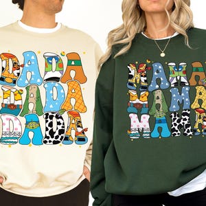 two people wearing sweatshirts with colorful, cartoon-style text.
