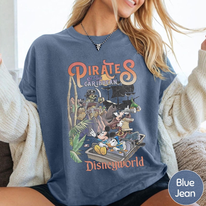 A woman wearing a blue t-shirt with a graphic of Disney's Pirates of the Caribbean on it.