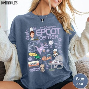 A woman wearing a blue t-shirt with various Disney-themed graphics and text, including a chef, roller coaster, and other iconic elements.