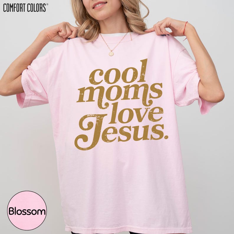 A woman wearing a pink t-shirt with the text "cool moms love Jesus" printed on it.