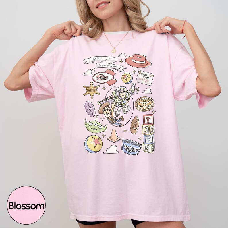 A woman wearing a pink t-shirt with various cartoon characters and icons printed on it, including a character from the Toy Story franchise.