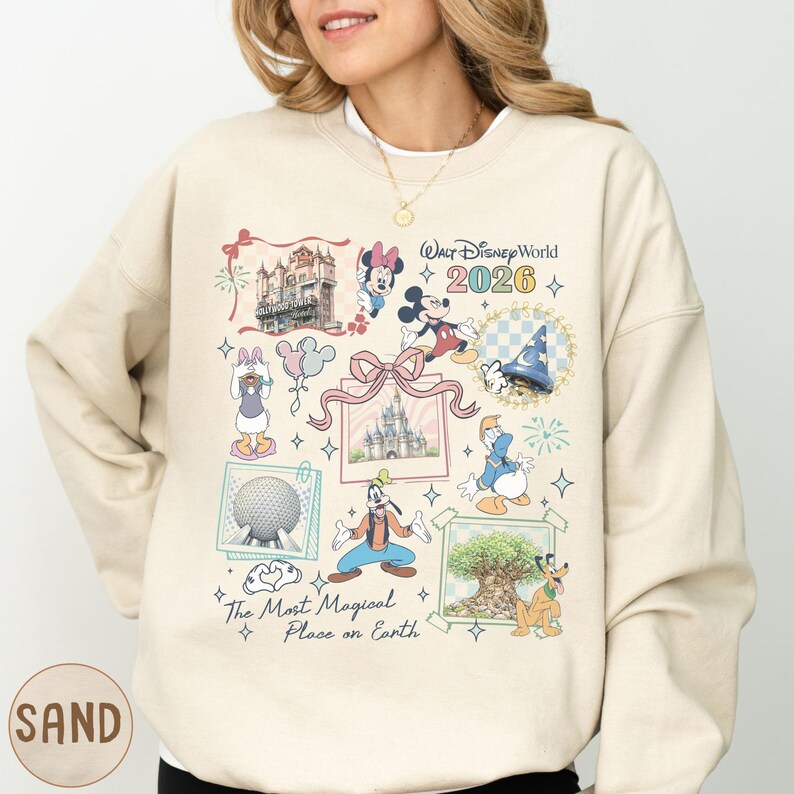 A woman wearing a beige sweater with a collage of Disney-themed illustrations and text, including characters like Minnie Mouse, Mickey Mouse, Donald Duck, and Goofy.