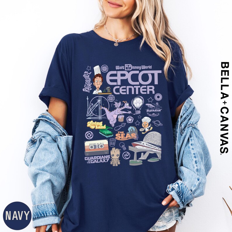 A woman wearing a navy blue t-shirt with various Disney-themed graphics and text, including a chef, roller coaster, and other iconic elements.
