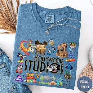 A blue t-shirt with various Disney and Pixar-themed graphics and logos, including characters, landmarks, and products associated with the Disney and Pixar franchises.