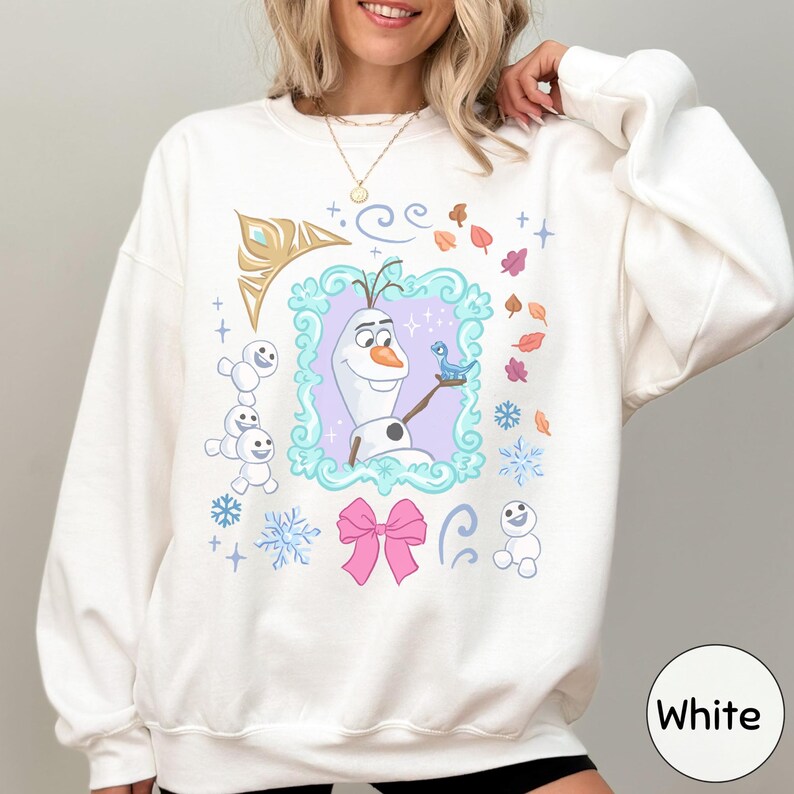 A woman wearing a white sweater with a colorful graphic design featuring characters from the Disney movie Frozen.