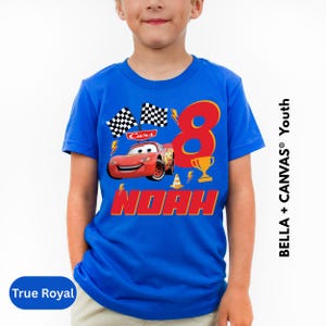 A young boy wearing a blue t-shirt with a design featuring the character Lightning McQueen from the movie Cars.
