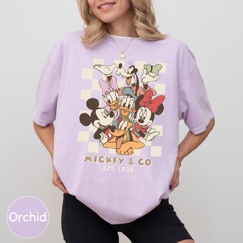 A woman wearing a purple t-shirt with a graphic of Disney characters Mickey Mouse and Donald Duck.