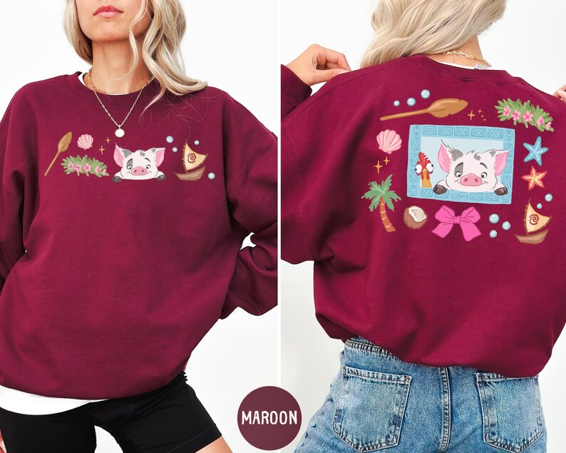 A woman wearing a burgundy sweatshirt with a cartoon pig design and various other decorative elements.