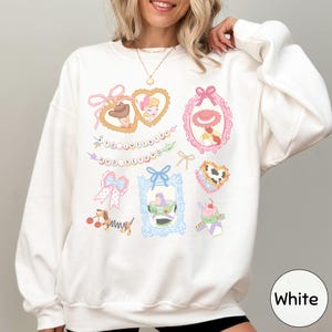 A woman wearing a white sweatshirt with various colorful illustrations and text on it.