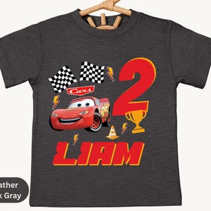 A gray t-shirt with a design featuring the character Lightning McQueen from the Cars movie, along with a number 2 and the text "Liam".
