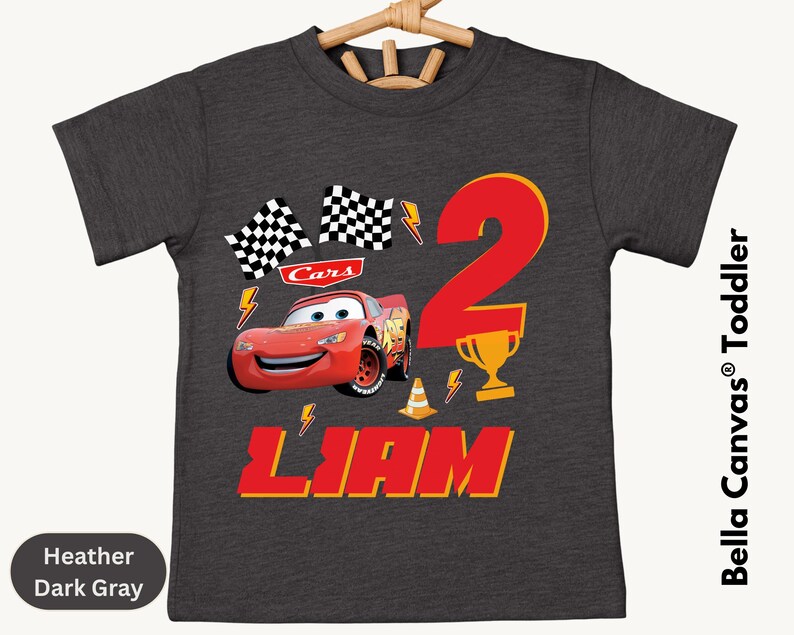 A gray t-shirt with a design featuring the character Lightning McQueen from the Cars movie, along with a number 2 and the text "Liam".