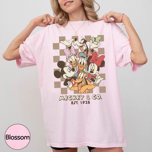 A woman wearing a pink t-shirt with a graphic of Disney characters Mickey Mouse and Donald Duck.