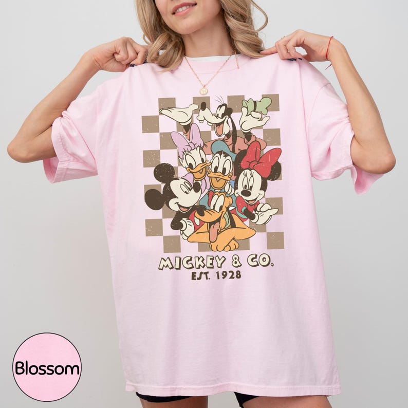 A woman wearing a pink t-shirt with a graphic of Disney characters Mickey Mouse and Donald Duck.